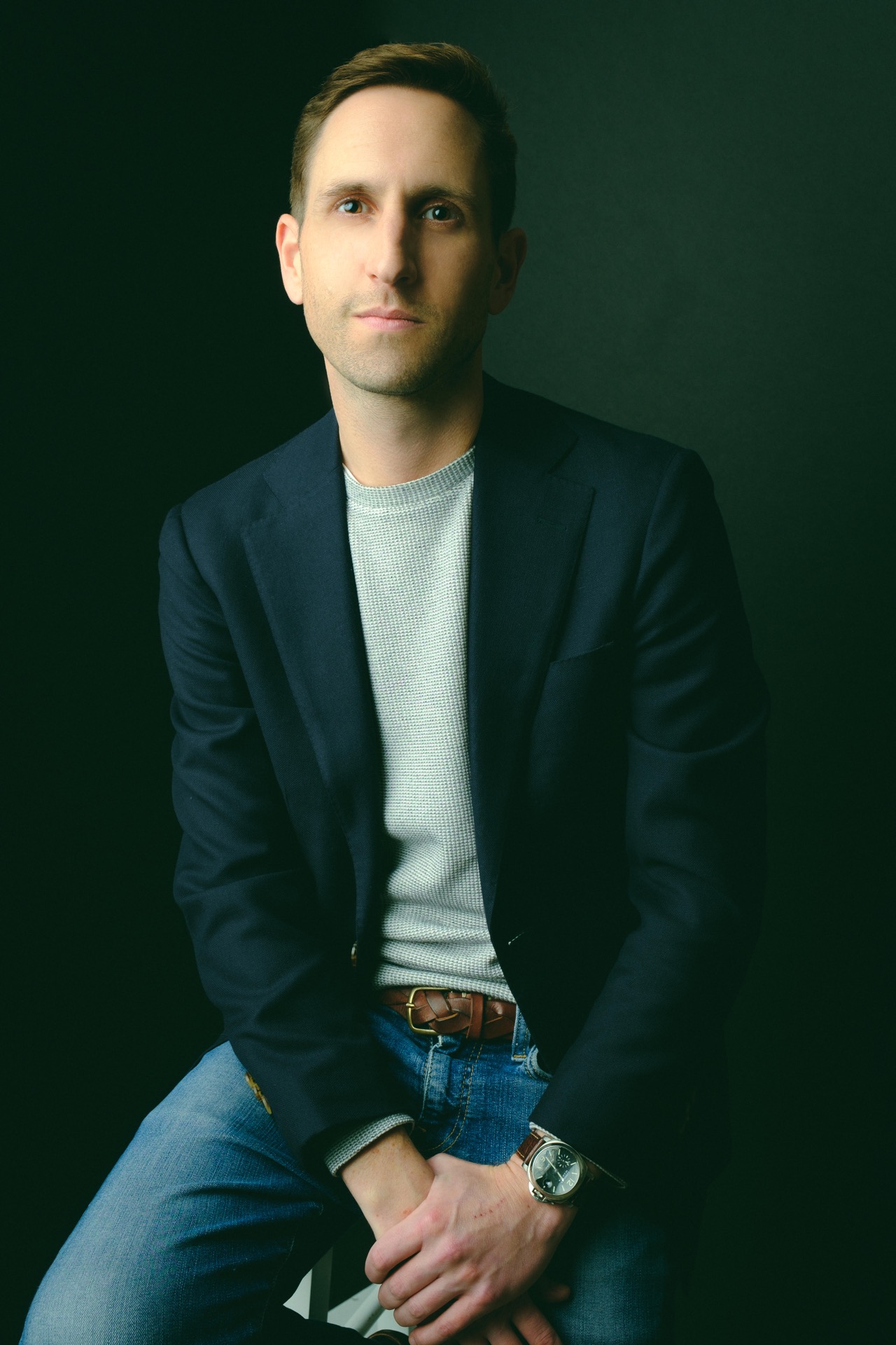 Portrait of Will McGuinness seated against a dark green background